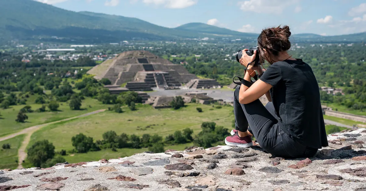 A young woman is taking a photo of the Pyramid of the Sun in Teotihuacan, Mexico