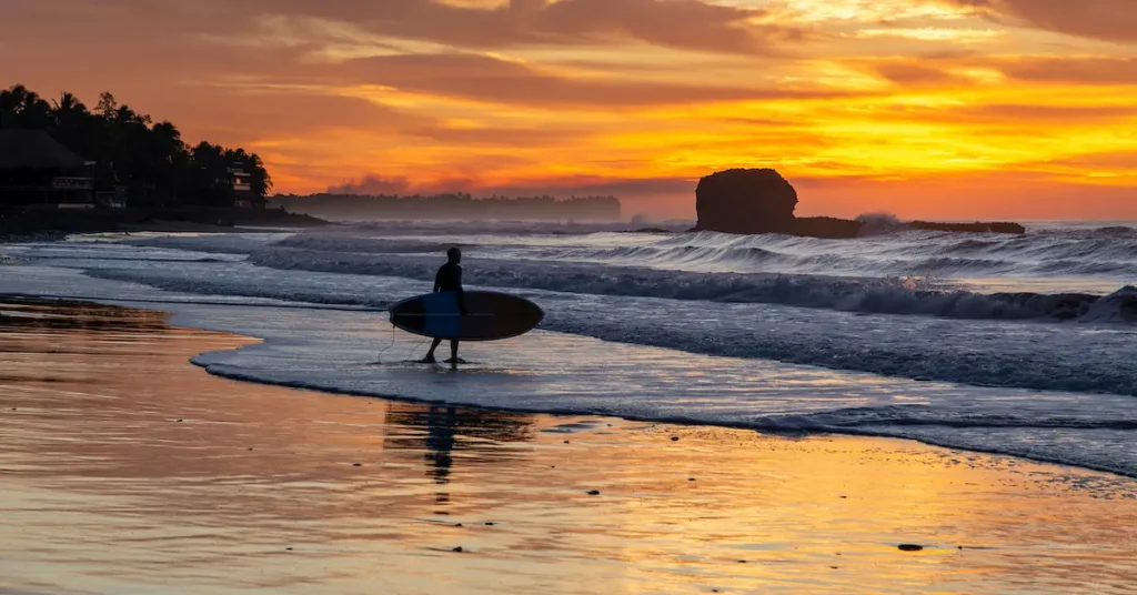 A surfer walks to the waves of El Tunco beach