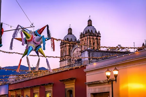 A colorful Mexican piñata with the cathedral of Oaxaca in the background during sunset