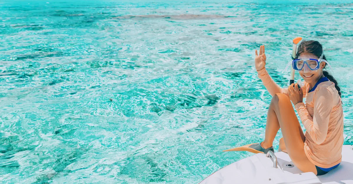 A young girl is sitting in a boat and ready to go snorkeling in the Caribbean Ocean
