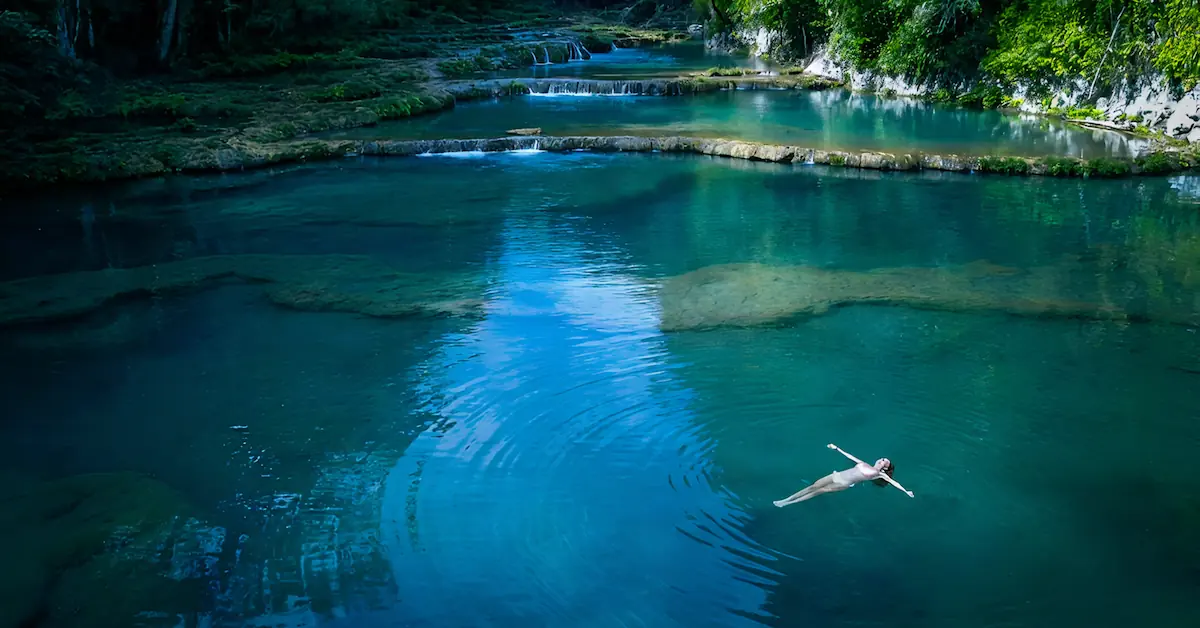 A young woman is lying and floating in the natural pools of Semuc Champey