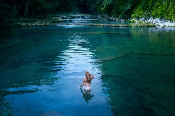 A young woman is in the natural pools of Semuc Champey