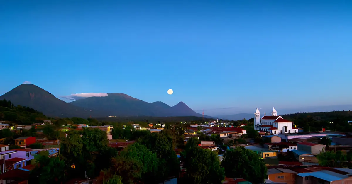 Aerial view of the town of Juayua at dusk with the moon and volcanoes of Cerro Verde in the background