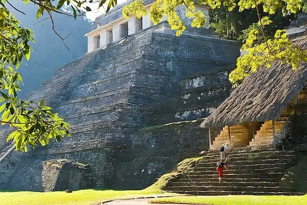 Two tourists are climbing stairs next to the temple of the Inscriptions in Palenque