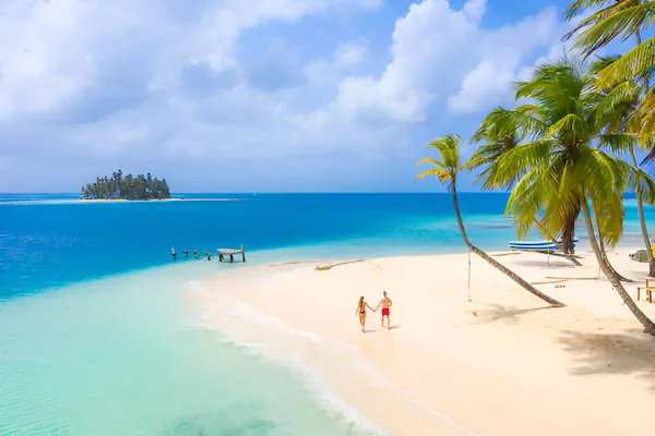 A couple is walking in a small deserted island facing another one in San Blas Panama