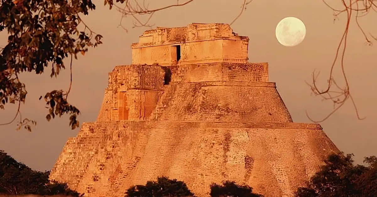 The pyramid of the Magician in Uxmal at dusk with the moon in the background
