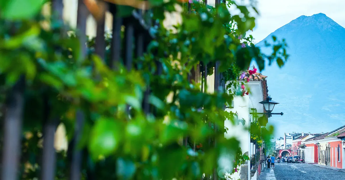A view of one of the colonial cobblestone street in Antigua Guatemala with the majestic Volcano de Agua in the background