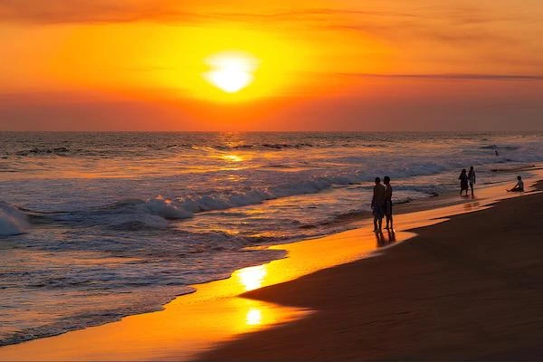 A few vacationer looks at the amazing sunset in the black sand beach of Monterrico