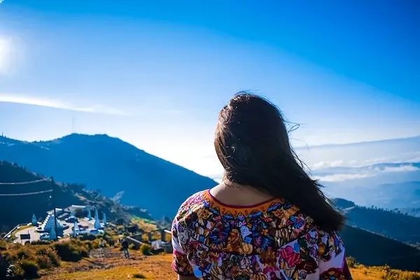 A young Maya woman wearing traditional clothing is looking at the mountains in the mountains close to Todos Santos