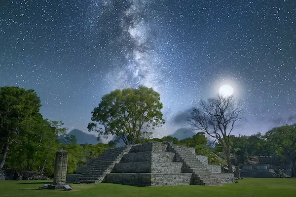 One of the temples in Copan ruins during a night with a sky full of stars and the full moon