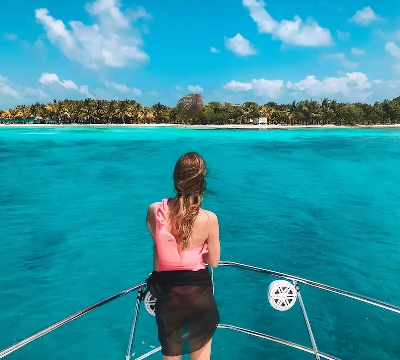 A girl is standing in a sailing boat looking at an island during an island hopping tour in Belize