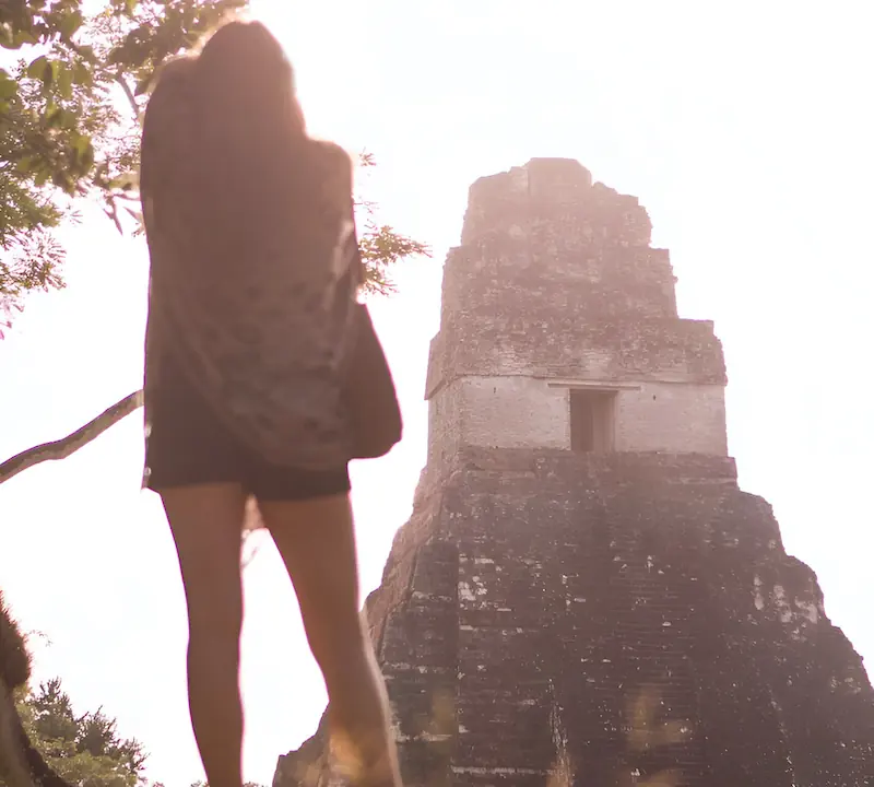 A woman is looking at Temple I in Tikal after sunrise