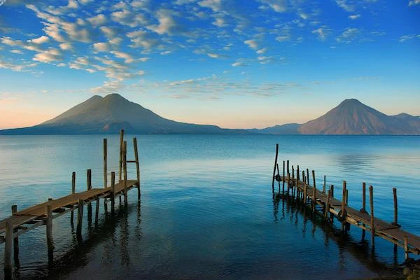 A view of the blue waters of Lake Atitlan, its volcanoes and two wooden docks