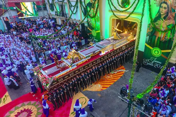 Devotees in purple robes carry the procession of Candelaria as it emerges from the church doors.
