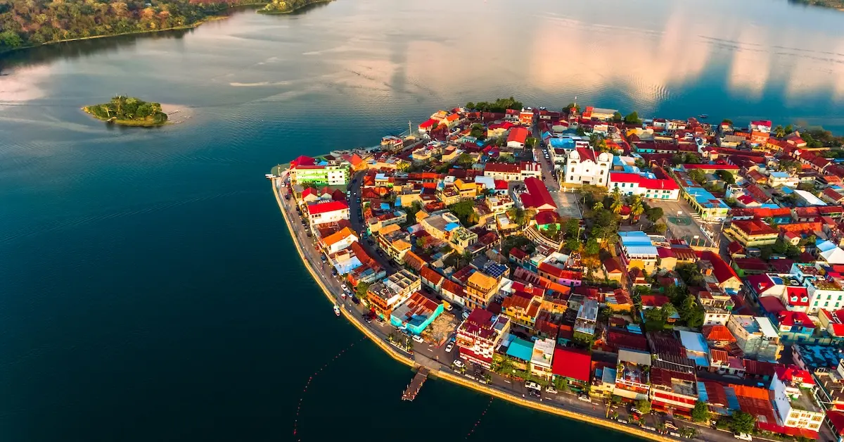 Aerial view of Flores Island in Lake Peten Itza, featuring colorful homes and the Cathedral of Our Lady of Los Remedios.