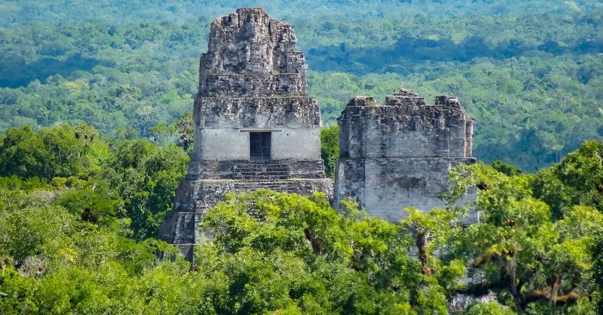 The Great Jaguar and Masks temples emerging from the jungle canopy at Tikal, Guatemala.